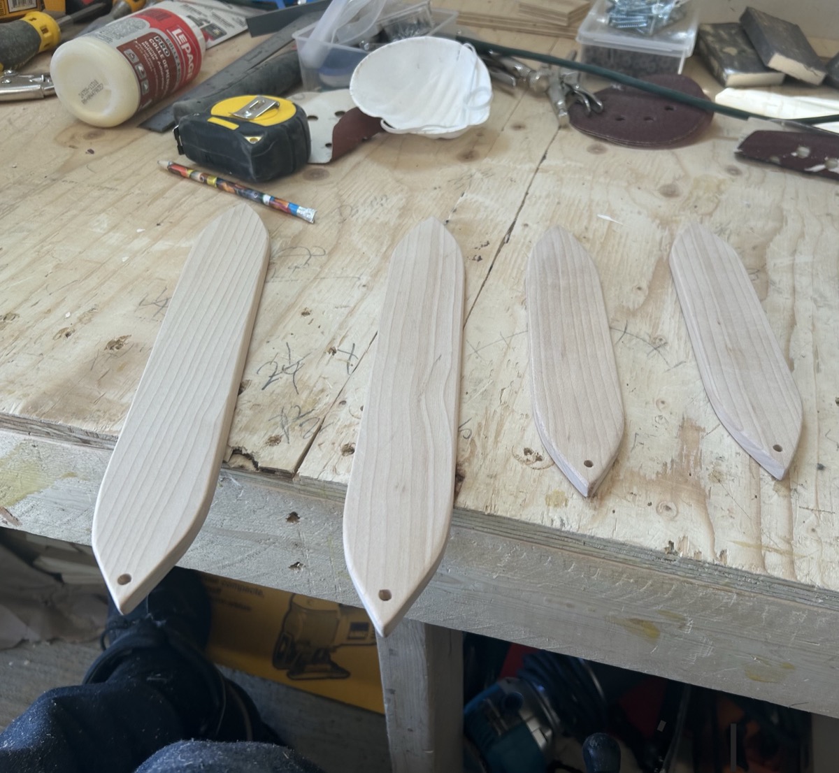 Four handcrafted bullroarers of different sizes on workbench by Ottawa Handiman